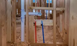 Instalacja hydrauliczna w budowie. Rury PEX (czerwona i niebieska) oraz biała rura kanalizacyjna. Widać złączki PEX, ale różnica między U i TH nie jest widoczna.