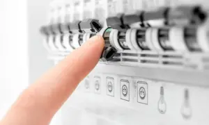 Palec naciska na zielony wskaźnik rozłącznika bezpiecznikowego w tablicy elektrycznej.