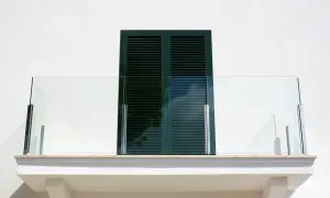 Nowoczesna obróbka balkonu z przeszkloną balustradą i okapnikiem.