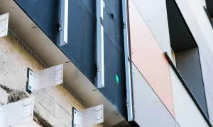 System mocowania elewacji wentylowanej. Metalowe wsporniki przytwierdzone do betonowej ściany, tworzące przestrzeń wentylacyjną pod panelami elewacyjnymi.