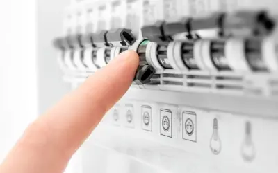 Palec naciska na zielony wskaźnik rozłącznika bezpiecznikowego w tablicy elektrycznej.
