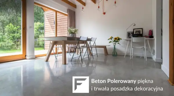Nowoczesne wnętrze z betonem polerowanym na podłodze. Stół, krzesła, biurko i okna z widokiem na ogród.