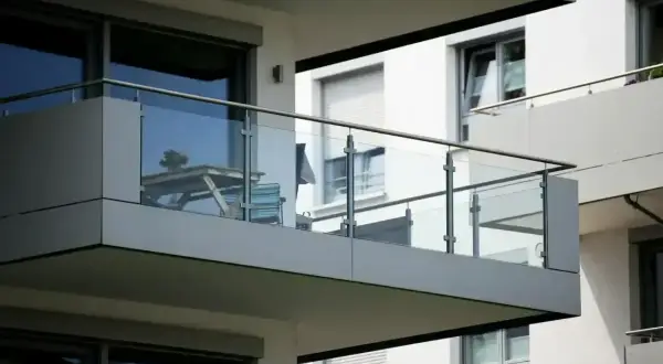 Nowoczesna loggia z przeszkloną balustradą, na której stoi stolik z krzesłami.