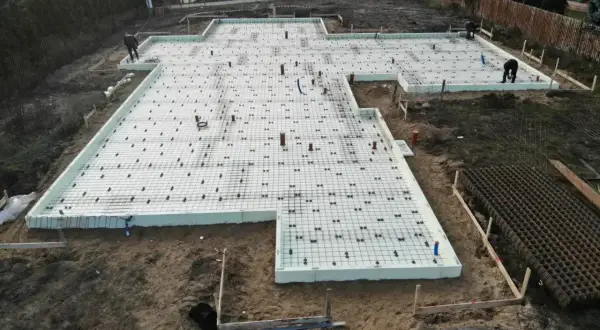 Budowa fundamentów z płyt izolacyjnych i zbrojenia. Szybki beton wkrótce zaleje tę konstrukcję, tworząc solidną podstawę.