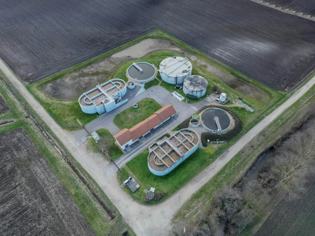 Widok z lotu ptaka na przepompownię ścieków domową z betonowymi zbiornikami i budynkiem.