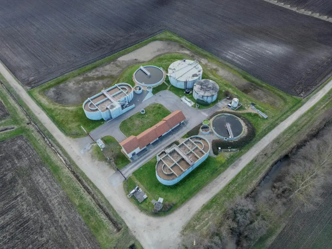 Widok z lotu ptaka na przepompownię ścieków domową z betonowymi zbiornikami i budynkiem.