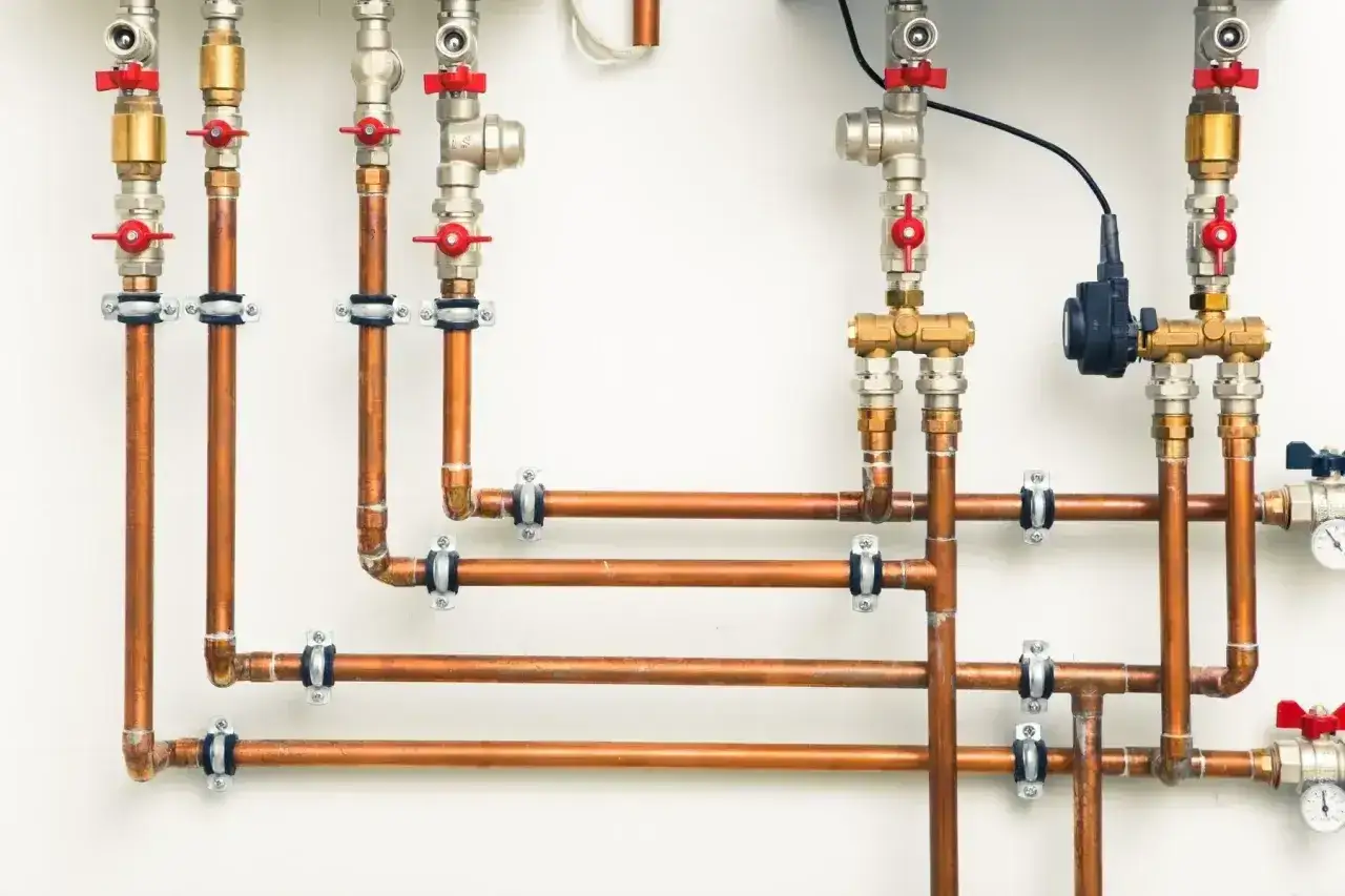 System hydrauliczny z miedzianymi rurami i zaworami. Złączki PEX U czy TH – różnica w montażu widoczna na połączeniach.