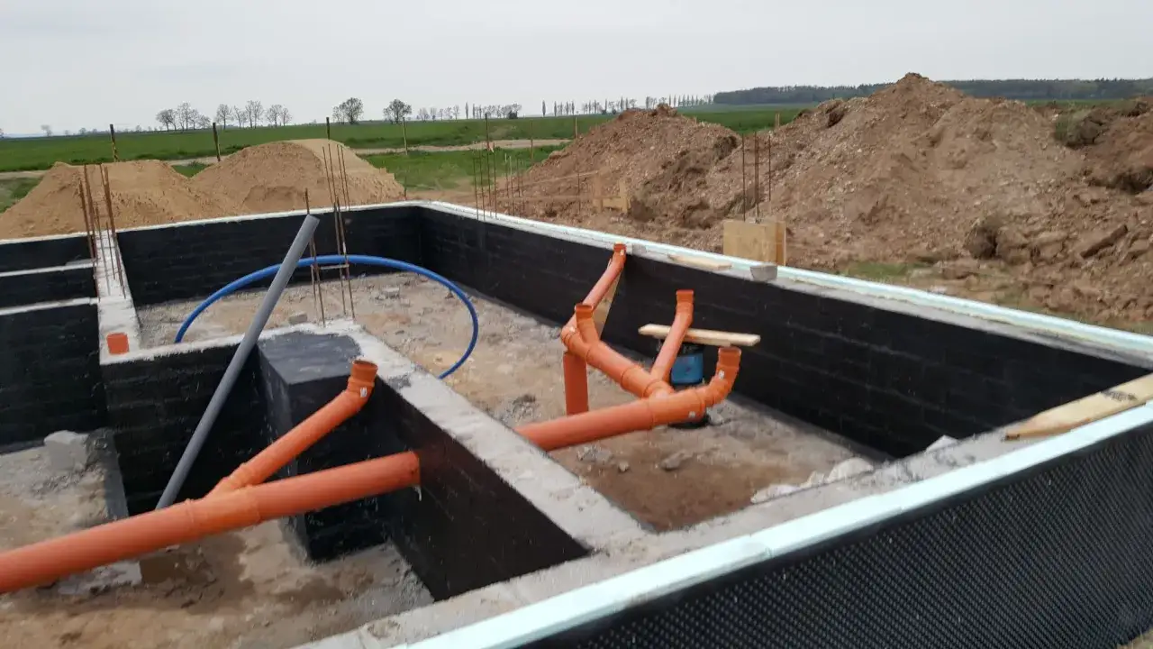 Budowa kanalizacji w fundamentach domu. Pomarańczowe rury tworzą skomplikowany system odprowadzania ścieków.