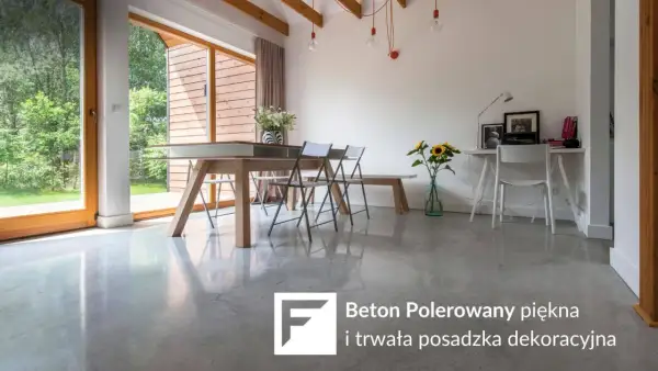 Nowoczesne wnętrze z betonem polerowanym na podłodze. Stół, krzesła, biurko i okna z widokiem na ogród.