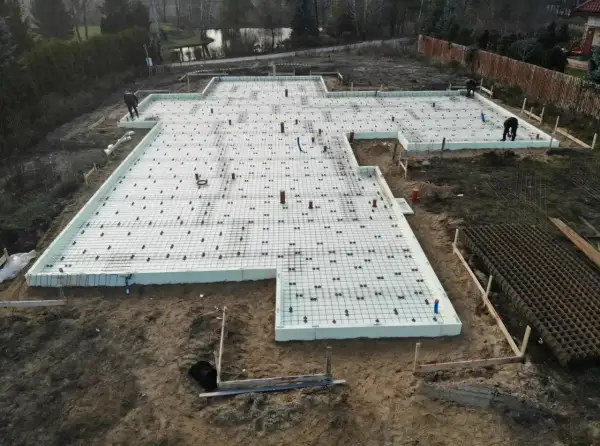 Budowa fundamentów z płyt izolacyjnych i zbrojenia. Szybki beton wkrótce zaleje tę konstrukcję, tworząc solidną podstawę.