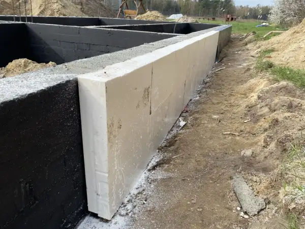 Fundament izolowany płytami ze styropianu ekstrudowanego, który jest rodzajem elastomeru. Czarna ściana fundamentowa pokryta hydroizolacją.